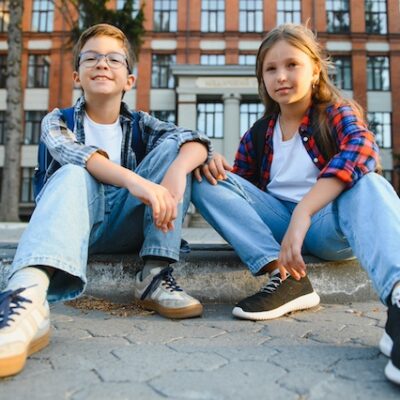 Two children sitting on a kerb.