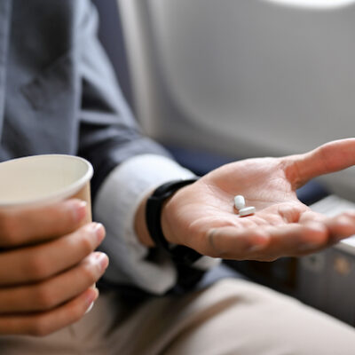 A man holding a paper cup and pills.