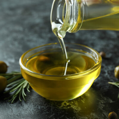 Olive oil pouring from bottle to bowl, close up.