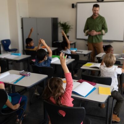 Children in a classroom raising their hands.