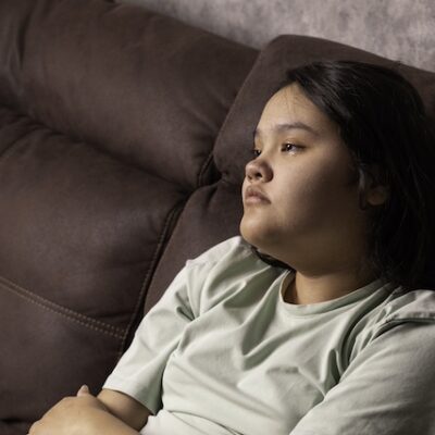 Girl sitting on a sofa looking sad.