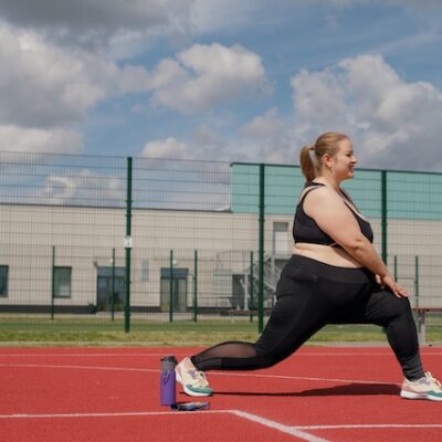 Woman stretching and squatting on an athletics track.