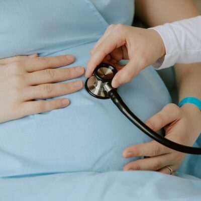 Doctor using a stethoscope on a pregnant woman.