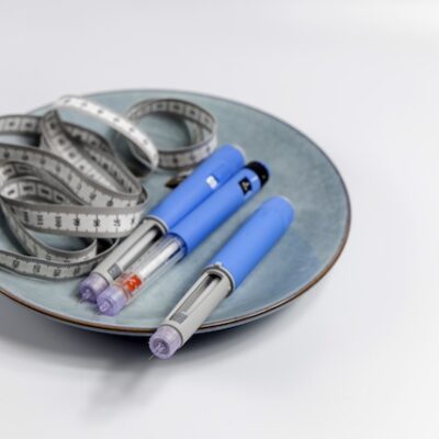 Ozempic Insulin injection pens on a plate with a measuring tape.