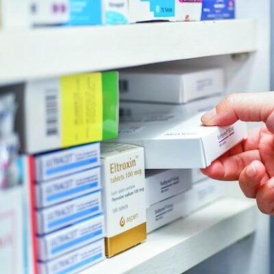 Pharmacist taking medication off of a pharmacy shelf.